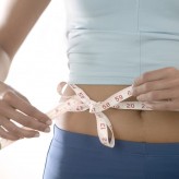 Woman Tying Measuring Tape Around Her Waist